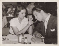 Lighting up ... Robert Taylor and Barbara Stanwyck, soon to be seen in a new M.G.M. picture. (Robert Taylor és Barbara Stanwyck, a '30-as évek Hollywoodjának egyik álompárja az M.G.M- nél, reggelizés után vagy előtt, közben.) [Original Press-Photo]